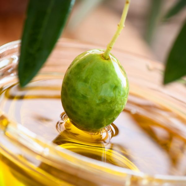 Extra virgin healthy Olive oil with fresh olives on rustic wooden background